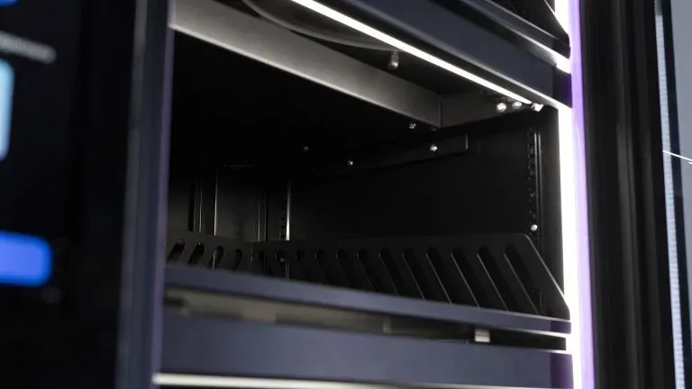 Empty shelf with a slotted front edge inside a cabinet, LED lighting above