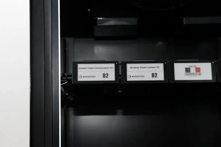 Electronic shelf labels on the front edge of an empty shelf inside a cabinet