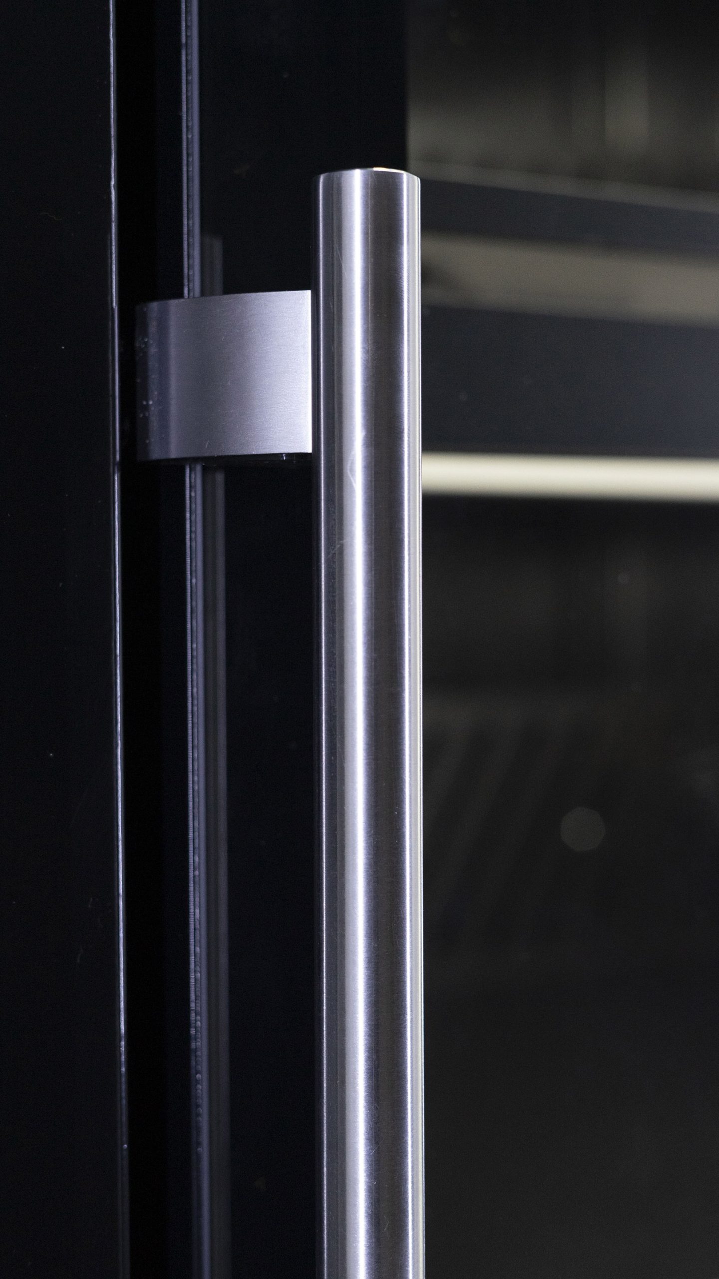 Vertical metal handle on the glass door of a cabinet
